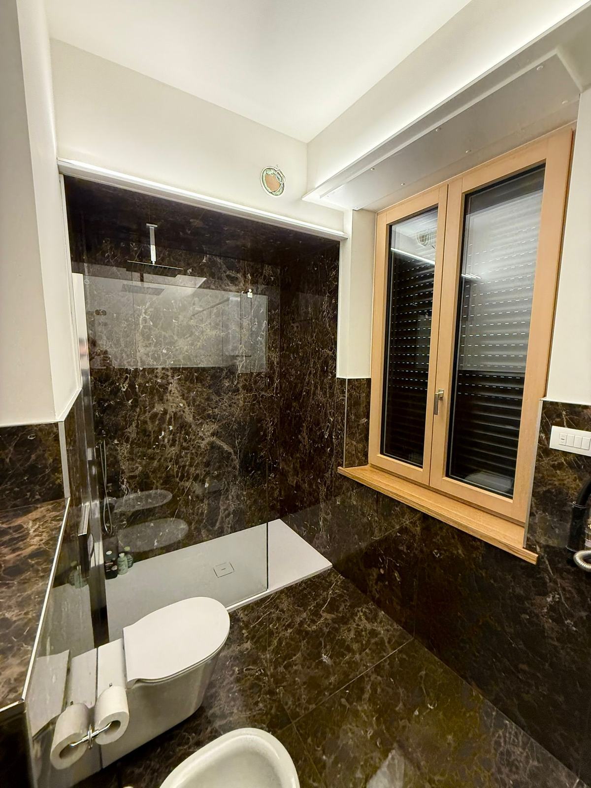 Doccia walk-in filo pavimento in marmo scuro — Ristrutturazione · Verona